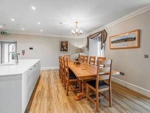 A dining area with a wooden table and chairs, a chandelier, and a framed picture on the wall. - Blairmains Farmhouse (Stirling)