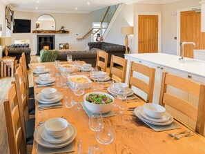 A dining area with a long wooden table set for a meal, surrounded by wooden chairs. - Blairmains Farmhouse (Stirling)