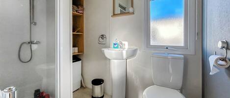 A bathroom with a shower, sink, toilet, and a window with a view.