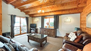 Sala de estar com sofás de couro, mesa de centro, televisão e armários de madeira.