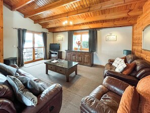 Ein Wohnzimmer mit Ledersofas, einem Couchtisch, einem Fernseher und Holzschränken.
