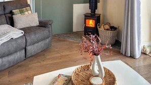 A cozy living room with a sofa, a fireplace, a lamp, and a vase with dried flowers. - 3 bedroom accommodation in Boncath (Boncath)