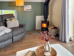 A cozy living room with a sofa, a fireplace, a lamp, and a vase with dried flowers. - 3 bedroom accommodation in Boncath (Boncath)