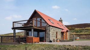 Ein Haus aus Stein mit rotem Dach, einem Balkon und einem Schornstein.