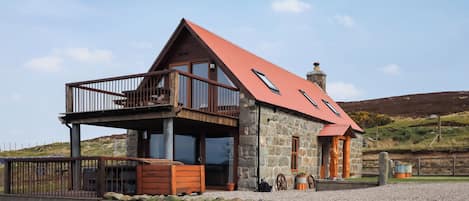 A stone house with a red roof, a balcony, and a chimney.