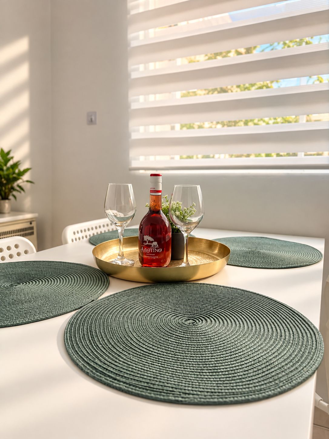 A dining table with a bottle of red wine, two glasses, and a gold tray.