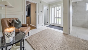 Un interior moderno con un sillón de cuero, una mesa de vidrio con una vela y una alfombra grande.