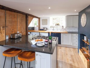 Una cocina moderna con una isla central, taburetes de bar, estufa y fregadero.