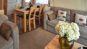A cozy living room with a dining area, a sofa set, and a vase with flowers on a table.