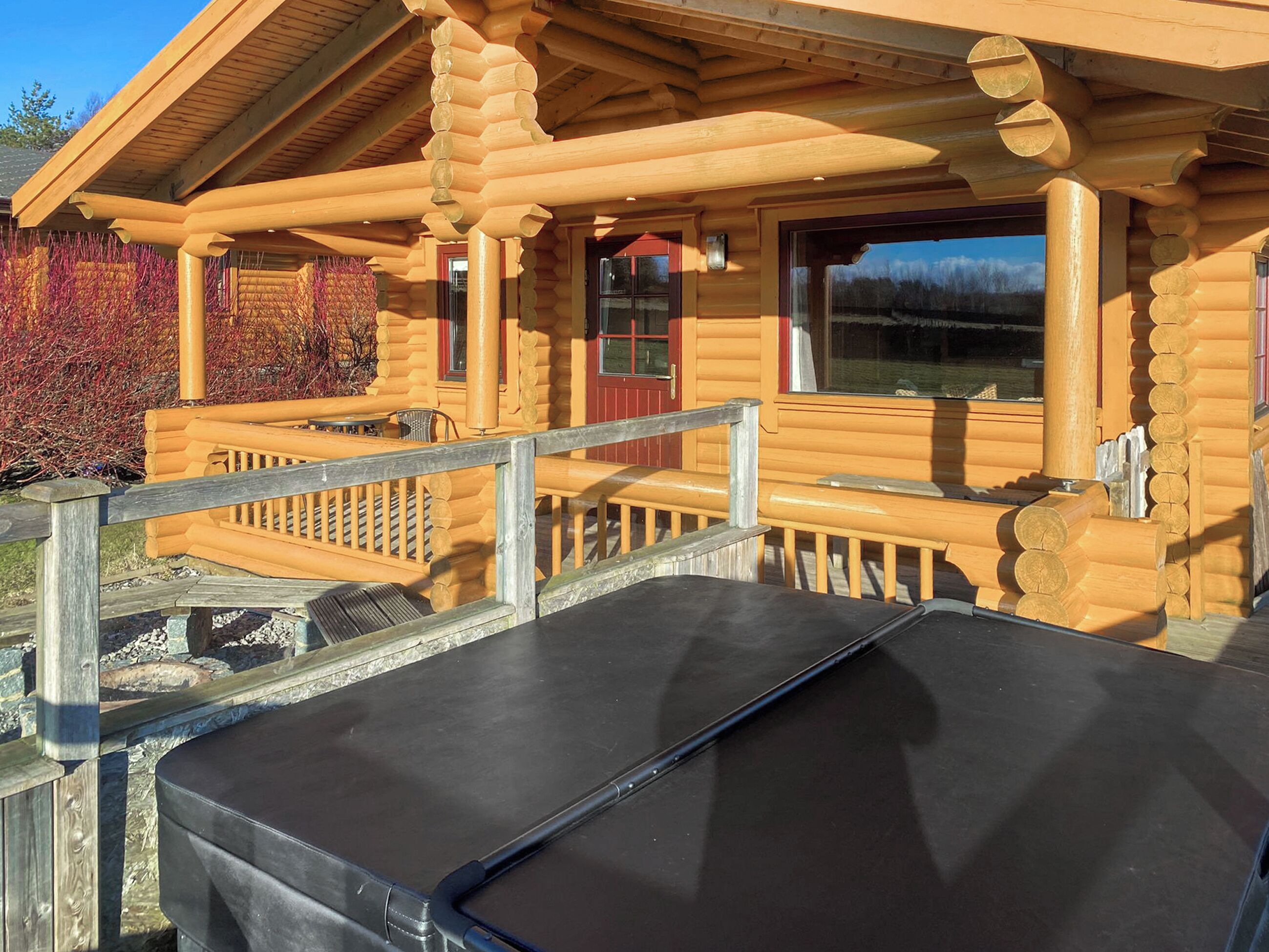 A log cabin with a wooden deck and a covered outdoor seating area.