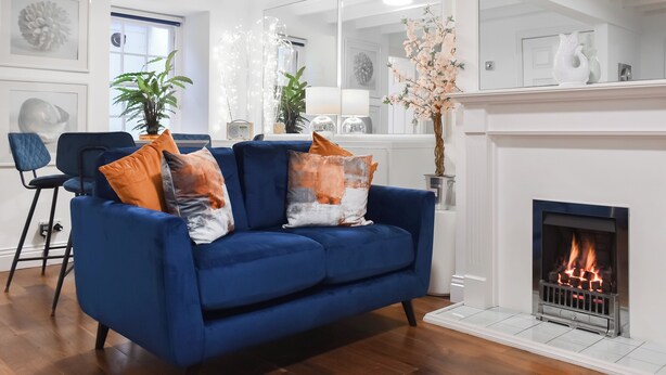 A living room with a blue sofa, a fireplace, and a large mirror. - 2 bedroom accommodation in Whitby (Whitby)