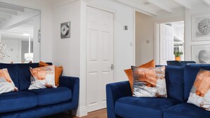 A room with a blue sofa set, a white door, and a mirror on the wall. - 2 bedroom accommodation in Whitby (Whitby)