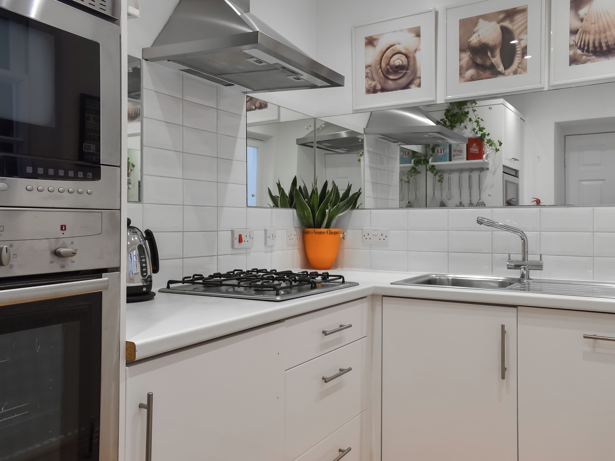 A kitchen with white cabinets, a gas stove, a microwave, and a sink.