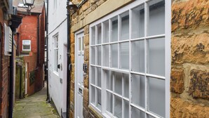 A narrow alleyway with a white door and a large window with multiple panes. - 2 bedroom accommodation in Whitby (Whitby)