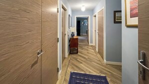 A hallway with wooden doors, a blue rug, and a framed picture on the wall. - Northbeach Apartment B (Prestwick)