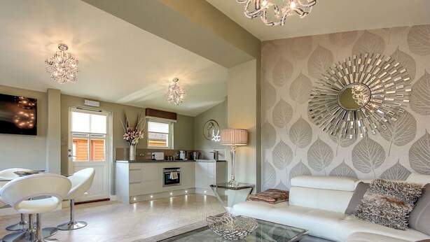 Una sala de estar moderna con una mesa de centro de vidrio, sofás blancos y un elemento decorativo en la pared.