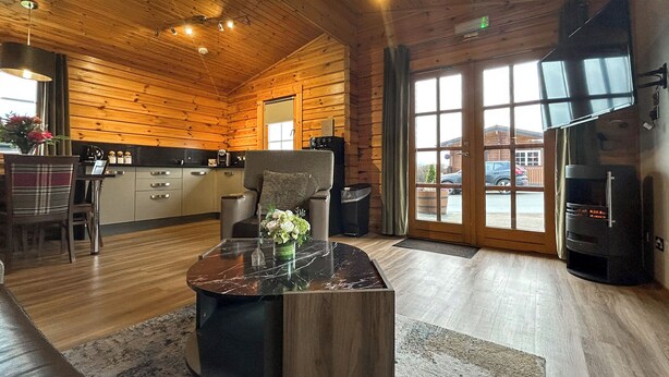 Interior de una cabaña de madera con cocina, comedor y chimenea.