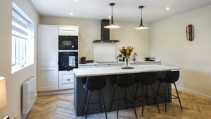 A modern kitchen with a central island, black bar stools, and pendant lighting. - 2 bedroom accommodation in Chirk, near Llangollen (Chirk, near Llangollen)