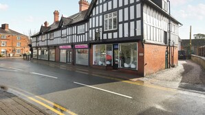 A traditional half-timbered building with multiple storefronts, including a hair salon and a beauty shop. - 2 bedroom accommodation in Chirk, near Llangollen (Chirk, near Llangollen)