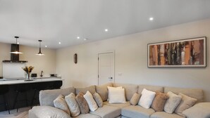 A modern living room with a beige sectional sofa, a wooden coffee table, and a kitchen area in the background. - 2 bedroom accommodation in Chirk, near Llangollen (Chirk, near Llangollen)
