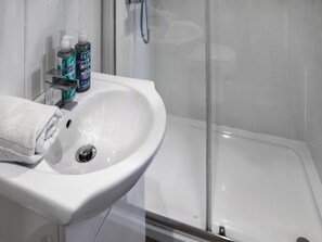 Een badkamer met een witte wastafel, twee flessen handzeep en een witte handdoek.