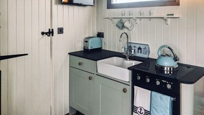 Uma cozinha compacta com pia, torradeira, chaleira e fogão.