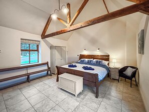 A bedroom with a wooden ceiling, a bed with striped bedding, a nightstand, a chair, and a bench. - 3 bedroom accommodation in Staunton-on-Wye (Staunton-on-Wye)