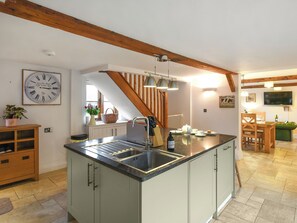 A kitchen with a central island, wooden beams, a clock, and a dining area with a TV. - 3 bedroom accommodation in Staunton-on-Wye (Staunton-on-Wye)