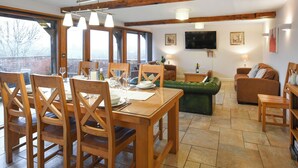 Zona pranzo con mobili in legno, un divano verde e una TV nel soggiorno.