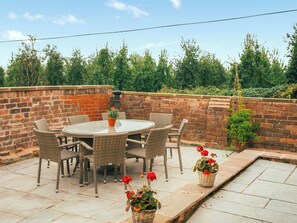 An outdoor patio with a round table and wicker chairs, surrounded by a brick wall and potted plants. - 3 bedroom accommodation in Staunton-on-Wye (Staunton-on-Wye)