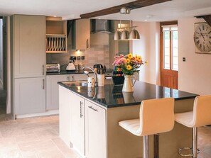 A modern kitchen with a central island, bar stools, and a clock on the wall. - 3 bedroom accommodation in Staunton-on-Wye (Staunton-on-Wye)