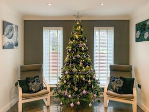 A living room with a decorated Christmas tree, two chairs, and a window with blinds. - 6 bedroom accommodation in Llanon, near Aberaeron (Llanon, near Aberaeron)