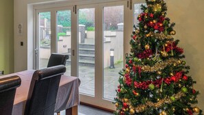 Un coin repas agrémenté d’un sapin de Noël décoré d’ornements et de guirlandes lumineuses.