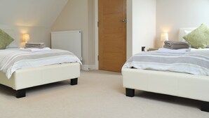 Une chambre avec deux lits, une porte en bois, un radiateur et une lampe.