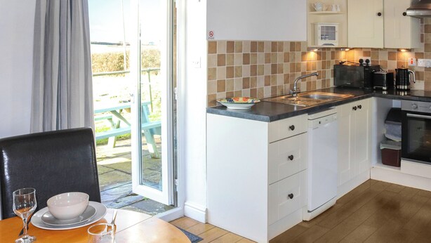 Una cocina compacta con comedor, una puerta corrediza de vidrio que da a un patio exterior y una decoración de peces en la pared.