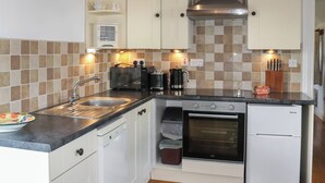 Una cocina compacta equipada con lavamanos, tostadora, hervidor, horno y un refrigerador pequeño.