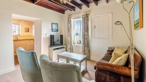 A living room with a TV, two armchairs, a sofa, a table, and a lamp. - Manor House Farm Cottage - UK49537 (Troutsdale near Scarborough)