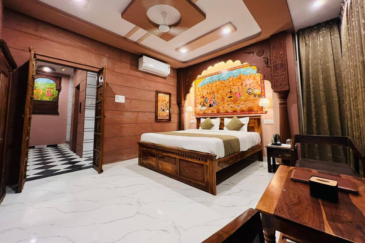 Une chambre d’hôtel avec un lit en bois, un bureau, une chaise, une fenêtre donnant sur un beau paysage et un élément décoratif mural.