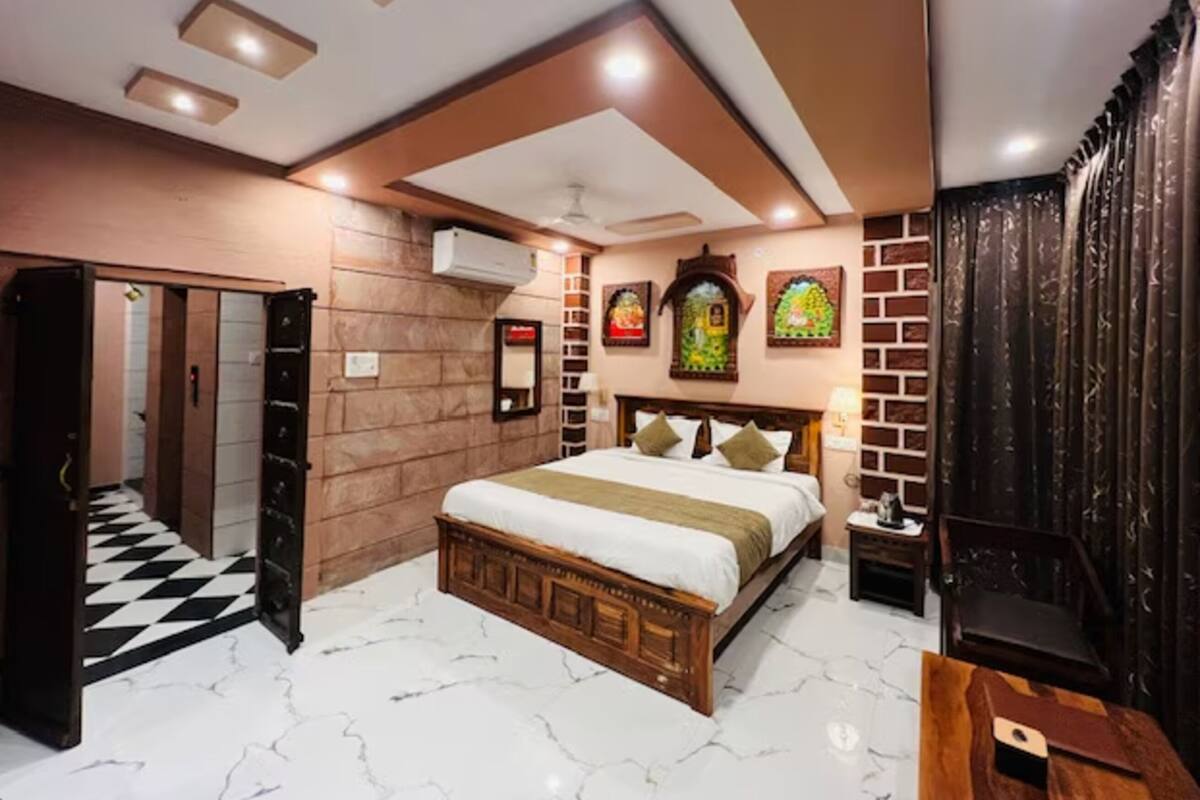 Une chambre d’hôtel dotée d’un grand lit, d’une tête de lit en bois, d’un sol en marbre et d’un plafond pourvu d’un éclairage encastré.