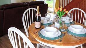 Une table à manger dressée avec de l’assiette blanche, des nappes vertes et une bouteille de champagne.