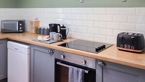 Une cuisine équipée d’un four à micro-ondes, d’un grille-pain, d’une bouilloire et d’une machine à café, le tout posé sur le plan de travail.