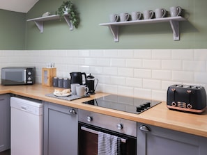 A kitchen with a microwave, toaster, kettle, and coffee maker on the counter. - Towy Cottage - UK49589 (Talley, near Llandeilo)