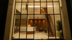 Une entrée moderne avec une façade en verre, un escalier et un espace d’accueil.