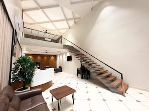 A spacious lobby with a staircase, a reception desk, and a seating area.