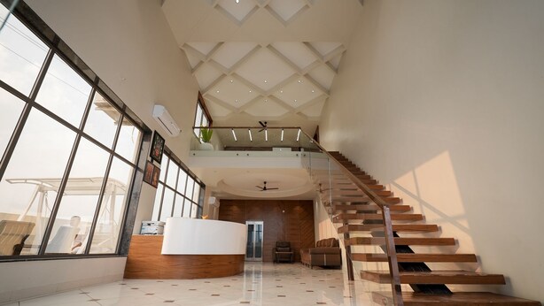 Un intérieur spacieux avec un plafond haut, un escalier central et un comptoir d’accueil.