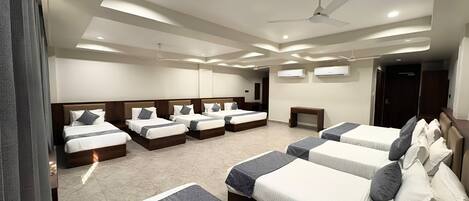A hotel room with multiple beds, a ceiling fan, recessed lighting, and an air conditioning unit.