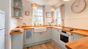 A kitchen with a wooden countertop, a sink, a stove, and a clock on the wall. - 2 bedroom accommodation in Beesands (Beesands)