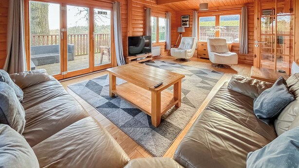 A spacious living room with a wooden floor, a large sofa set, a coffee table, and a television. - 4 bedroom accommodation in Kenwick, near Louth (Kenwick, near Louth)