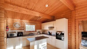 A modern kitchen with wooden walls, a central island, and built-in appliances. - 4 bedroom accommodation in Kenwick, near Louth (Kenwick, near Louth)