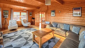 A cozy log cabin interior with a sofa, a wooden coffee table, and a patterned rug. - 4 bedroom accommodation in Kenwick, near Louth (Kenwick, near Louth)